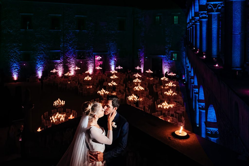 Bride and groom sharing romantic moment overlooking candlelit courtyard at night, Umbria wedding photographer capture