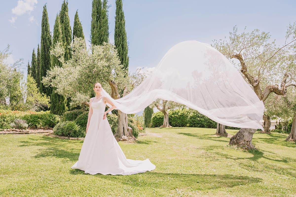 Bride in a flowing wedding dress with veil lifted by the wind at Villa San Crispolto, Umbria