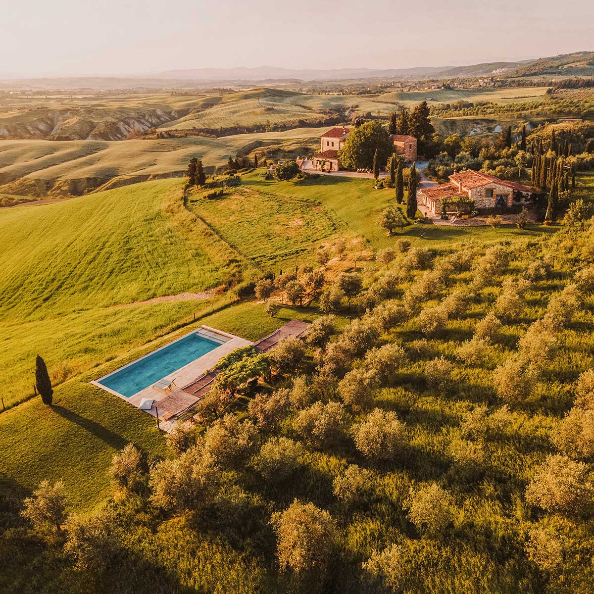 A breathtaking Tuscan estate at sunset, featuring olive groves, a swimming pool, and rolling hills, perfect for a budget-friendly wedding venue